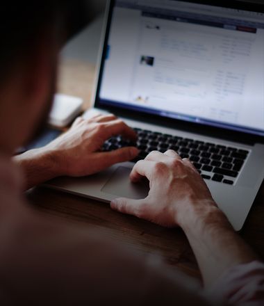A man is sitting and typing on a laptop keyboard