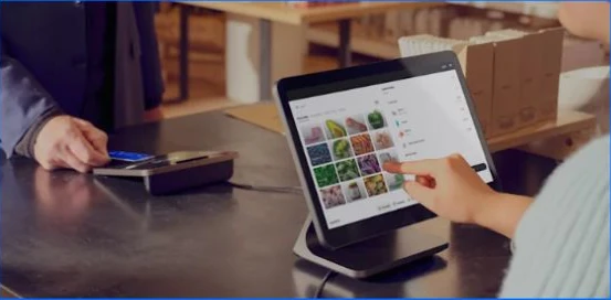Square point-of-sale display and card reader at a shop counter.